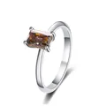 Macro shot of an emerald-cut amber moissanite stone set in a polished S925 silver ring band - Gray