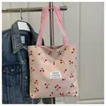 Dettaglio della borsa tote in velluto a coste rosa con stampe di ciliegie e manici in tessuto - Rosa