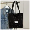 Dettaglio della borsa tote in velluto nero con stampa ciliegie ed etichetta bianca - Nero
