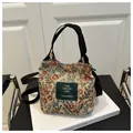 Détail d'un sac seau en jacquard floral avec anses en toile noire sur un livre blanc - Floral Rouge et Bleu (Style 3)