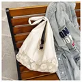 Large cream canvas tote bag with intricate floral crochet lace trim on a park bench - Off White