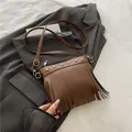 Borsa a secchiello marrone in ecopelle con frange e borchie su un blazer scuro - Marrone
