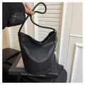 Détail du sac seau noir grainé avec chaîne argentée posé sur des livres d'art - Noir