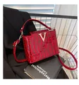 Close-up of red crocodile texture handbag with golden V buckle on a black suit jacket - Burgundy