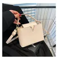 Detail van beige handtas met krokodillenreliëf en gouden V-sluiting op de kar - Broken Wit