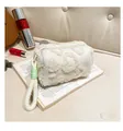 Detail view of plush white clutch bag with embossed heart patterns and green accents - White