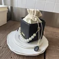 Elegant black woven bucket bag with cream drawstring liner and pearl top handle - Black