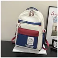 Detalle de mochila de lona color-block con bolsillos azul marino y granate sobre libros - Estilo Patchwork Azul y Rojo / Azul