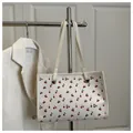 Dettaglio di una borsa tote bianca con stampe di ciliegie e occhielli in metallo dorato - Bianco