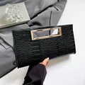 Elegant black crocodile-patterned clutch bag with a sleek silver metal cutout handle - Black