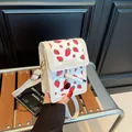 Mini white crossbody bag featuring red strawberry prints and elegant gold hardware - Strawberry White
