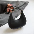 Bolso de media luna negro minimalista en cuero granulado con detalles metálicos dorados - Negro