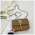 Detail of brown square bag with geometric embossing, gold logo, and tassel charm - Khaki