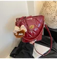 Detail of red quilted bucket bag with gold twist lock and plush monster charm - With Charm / Red