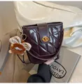 Macro view of purple quilted bucket bag with golden twist lock and plush monster charm - With Charm / Brown