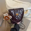 Quilted dark brown leather bucket bag with metal turn-lock and plush wing pendant - Without Pendant / Brown