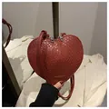 Detail of red heart-shaped woven crossbody bag with dual zippers and fashion texture - Red