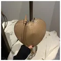 Detail view of heart-shaped tan crossbody bag with crocodile embossing and metal lettering - Khaki