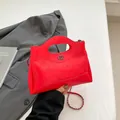Red quilted leather handbag with chain strap and metallic ring detail in a tilted view - Red