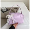 Detail of lavender underarm bag with pearl lace bow charm on white bedding - With Ornament / Purple
