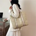 Minimalistische Stroh-Einkaufstasche mit breiten Canvas-Schultergurten am Modell - Weiß