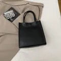 Minimalist black PU leather tote bag with circular buckle and sturdy dual handles - Black