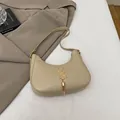 Beigefarbene Halbmond-Achseltasche mit goldenem Logo und Quastenkettendetail - Khaki