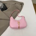 Rosa Halbmondtasche mit goldenem SS-Logo und Metallquaste in stilvollem Ambiente - Rosa