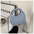 Close-up of light blue crescent handbag with vertical texture and gold hardware - Blue