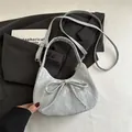 Bolso medialuna gris claro con detalle de lazo sobre una chaqueta de traje gris - Plateado
