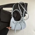 Hellblaue Halbmond-Handtasche mit Marmorstruktur und Schleife auf grauem Blazer - Blau