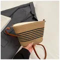Bolso saco de paja con rayas negras y correa de cuero marrón sobre tela blanca - Caqui y Negro