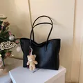 Black pebbled leather tote bag with long strap and cute beige bear charm accessory - Black With Pendant
