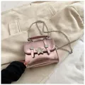 Metallisch-rosa Mini-Umhängetasche mit Sternverschluss und Silberkette auf Cordhintergrund - Rosa
