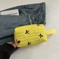 Bright yellow quilted pouch with black bow embroidery and a fabric wrist strap - Yellow