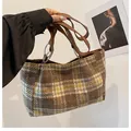 Detail of checkered tweed tote bag featuring brown leather handles and silver ring hardware - Khaki Plaid