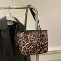 Detail of leopard print tote bag featuring black slim straps and golden rivet accents - Brown