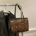 Detail of leopard print tote bag featuring black leather straps and gold rivet accents - Brown