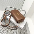 Bolso baguette de cuero marrón sobre un libro de moda para un aspecto retro clásico - café