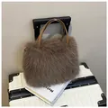 Bolso de piel sintética gris marrón con asas de cuero sobre una maleta blanca - café