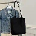 Minimalistische schwarze Wildleder-Beuteltasche mit langen Trägern an einer Jeansjacke - Schwarz