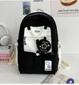 Detail eines schwarz-weißen Rucksacks mit Stern-Anhänger und vorderem Reißverschluss - Schwarz