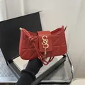 Chic red quilted crescent shoulder bag with golden tassel and metal monogram clasp - Red