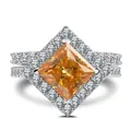Macro view of princess cut orange gemstone with halo setting on silver ring band - Size 6 / Champagne
