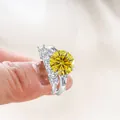 Primer plano macro de set de anillos con moissanita amarilla de 5ct sobre fondo de raso - Amarillo Dorado