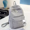 Detail of gray corduroy backpack with large front pocket and white bear pendant on a bed - With Bear Pendant / Light Gray