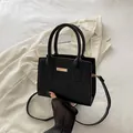 Elegant black stone textured mini handbag with gold metal detail on white suit - Black