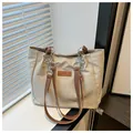Detalle de bolso tote beige con correas de cuero marrón y cadena de metal plateado - Caqui