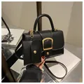 Detail van zwarte handtas met litchi-nerf, gouden gesp en bijpassende mini-pochette - Zwart