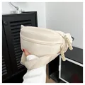 Close-up of minimalist cream crossbody bag showing woven rope zipper pulls and texture - Off White